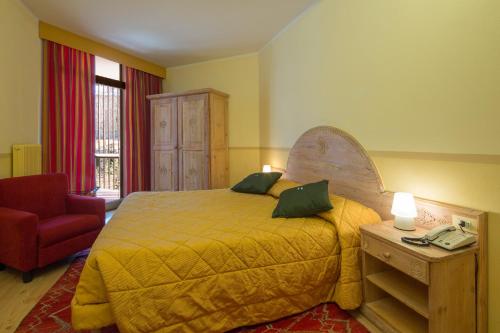 a bedroom with a large bed and a red chair at Hotel Portavescovo in Arabba