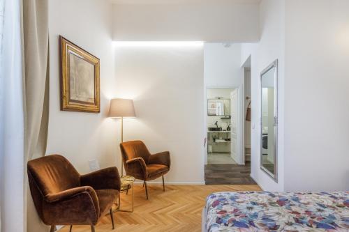 une chambre avec deux chaises, un lit et un miroir dans l'établissement PARMA EXPRESS Traveller's Lodging front Station FS PARKING & Bicycle Storage, à Parme