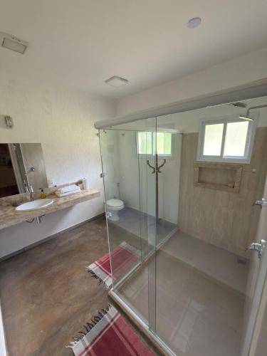 a bathroom with a glass shower and a sink at Morada do Ipê Pousada in Chapada dos Guimarães