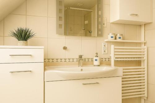 a white bathroom with a sink and a mirror at Kleine Auszeit Pellworm in Pellworm