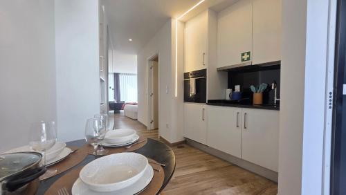 a kitchen with a table with plates and wine glasses at A Proa do Moliceiro - iConik Design Apartments in Aveiro