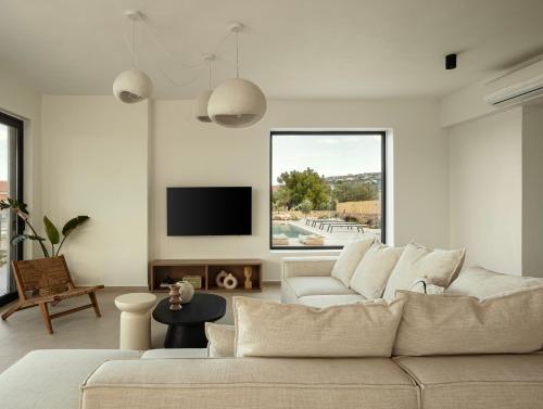a white living room with a couch and a tv at Plaka Oasis - Private Pool - Walk to Beach & Shops in Plaka