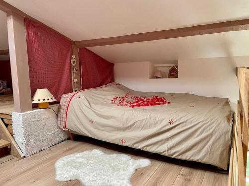 a bedroom with a bed with red flowers on it at Petit chalet rénové in Grandrif