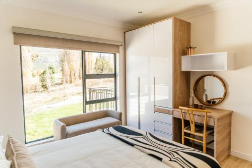 a bedroom with a bed and a mirror and a chair at Pause Guesthouse in Clarens