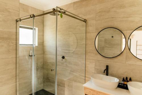 a bathroom with a shower and a sink and a mirror at Pause Guesthouse in Clarens