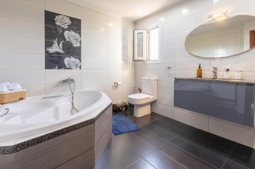 a white bathroom with a tub and a toilet at Aeolus Villa Chios in Chios