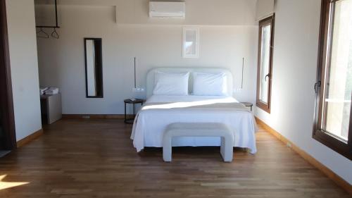 a white bed with a stool in a room at Ianos Living Spaces - 03 in Korinthos