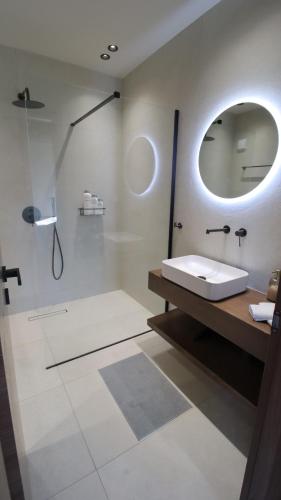 a bathroom with a sink and a shower with a mirror at Ianos Living Spaces - 03 in Korinthos