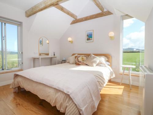 a white bedroom with a large bed and a window at Seren Fach in Pwllheli
