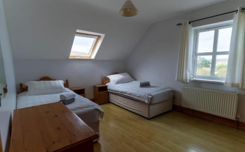 a room with two beds and a table and a window at Bray Head View 2 in Clynacartan