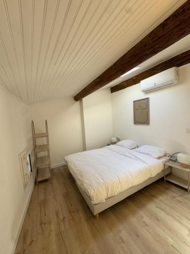 a bedroom with a white bed and a wooden floor at T3climatisé Hyper centre 2 Chambres Terrasse in Sète