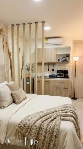 a bedroom with a large bed and a kitchen at Suites Privadas - Elite Valledupar, Cerca CC Guatapurí y Rio Guatapurí in Valledupar