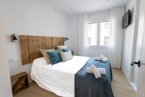 a bedroom with a large white bed with blue pillows at Apartamentos La Búsqueda in Cuenca