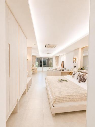 a white bedroom with a large bed and a living room at Green View Condo in Kathu