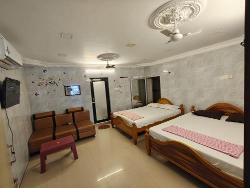 a bedroom with two beds and a couch and a tv at Kanchi grace cottage in Kanchipuram