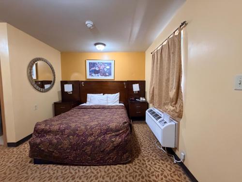 a hotel room with a bed and a mirror at Regal Inn Coffeyville KS US 169 in Coffeyville