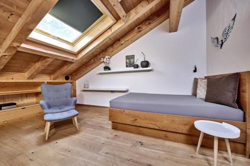 a bedroom with a bed and a chair and a window at Wally Luxus Lodge im Ferienhaus Magdalena in Mittenwald