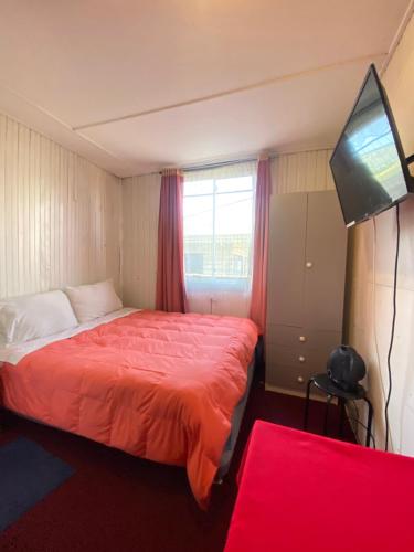 a bedroom with a bed and a flat screen tv at Hostal Cochrane in Valdivia