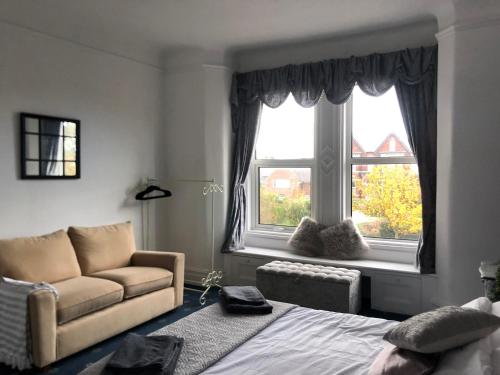 a bedroom with a bed and a couch and two windows at Apartments at 145 in Southport