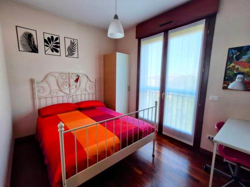 a bedroom with a bed with an orange and red blanket at Casa Mike - Trilocale con garage in San Giuliano Milanese