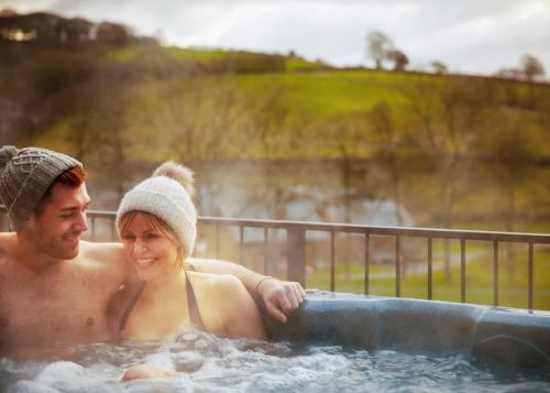 a man and a woman sitting in a hot tub at Benview Lodges in Kemnay