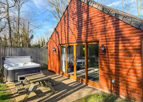a small red brick shed with a bench and a hot tub at Woodland Waters in Ancaster