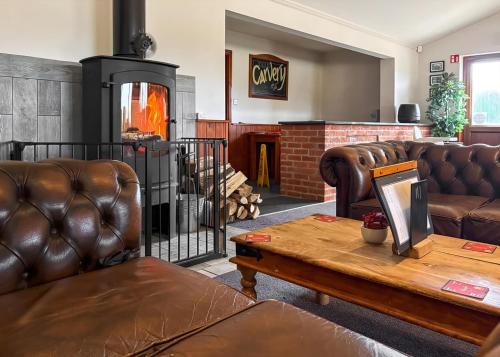 a living room with leather furniture and a fireplace at Woodland Waters in Ancaster