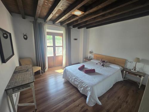 a bedroom with a white bed and a wooden floor at La Casona del Rio Abion in Valdealvillo
