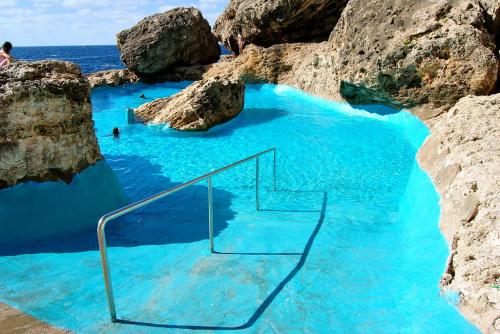 a swimming pool with blue water and rocks at Residencia Santiago Mallorca in Cala Figuera