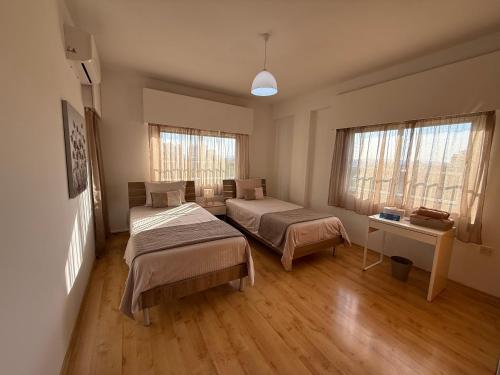 a bedroom with two beds and a desk and windows at City Vibes - Central 3BR Spacious Apartment in Larnaca