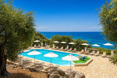 a swimming pool with umbrellas and chairs and the ocean at Nissaki Sea View Hotel in Corfu