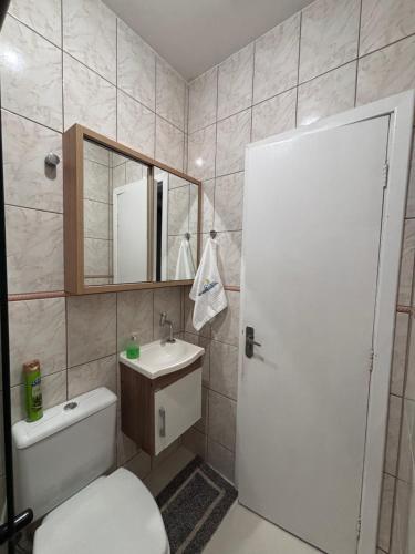 a bathroom with a toilet and a sink and a mirror at Casa com piscina Aquecida Balneário Camboriú CasaAlbertiBc in Balneário Camboriú