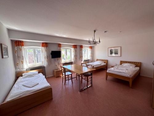 a room with two beds and a table and chairs at W&P Living Zi 5 Bräustüble FeWo 1 2OG l in Buttenwiesen