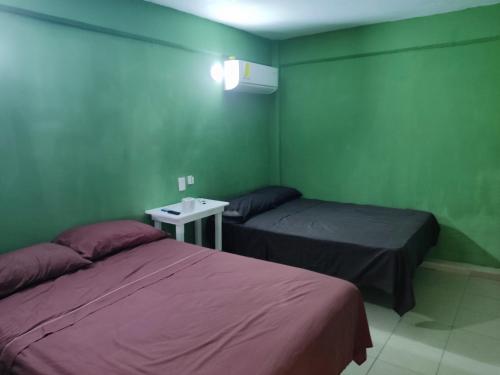 two beds in a room with green walls at Centro turístico la playitaa in Chachalacas