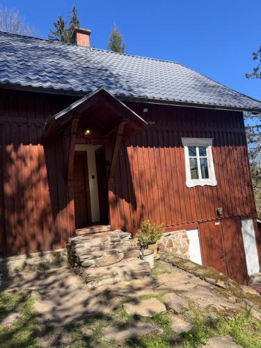 a red house with a door and a stone walkway in front at Chalupa Pod Skalou Relax in Paseky nad Jizerou
