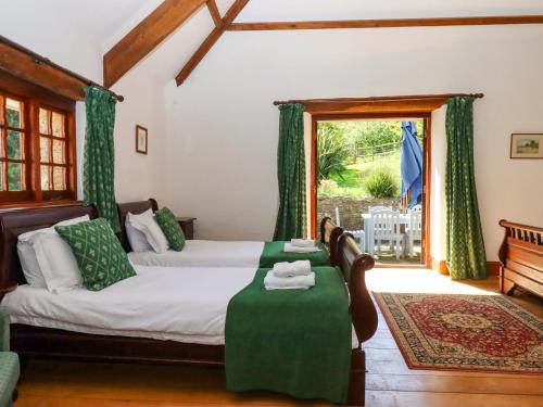 a bedroom with two beds with a table and a window at East Bickleigh in Totnes