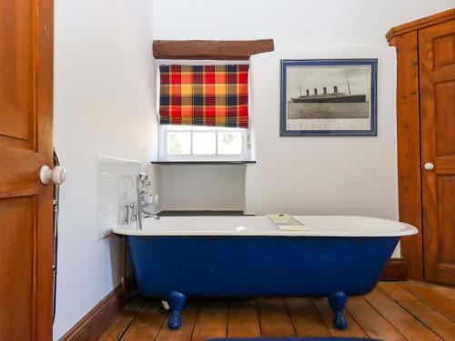 a blue bath tub in a bathroom with a window at East Bickleigh in Totnes