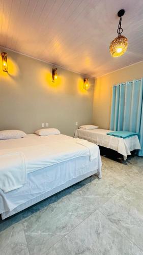 two beds in a room with blue curtains at Pousada Imperio Azul in Santo Amaro