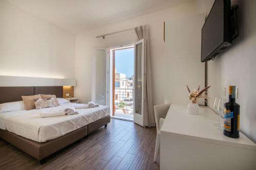 a bedroom with a bed and a large window at La Dimora del Passante in San Vito lo Capo