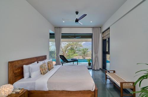 a bedroom with a large bed and a chair at SaffronStays Pickle & Play in Khandāla