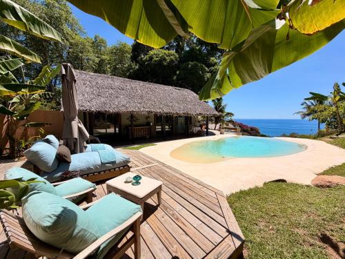a resort with a pool and a deck with chairs at Château de feuilles & SPA - Praslin island in Baie Sainte Anne