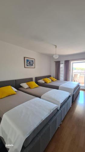 a room with three beds with yellow pillows at Studios Dolček in Krvavica