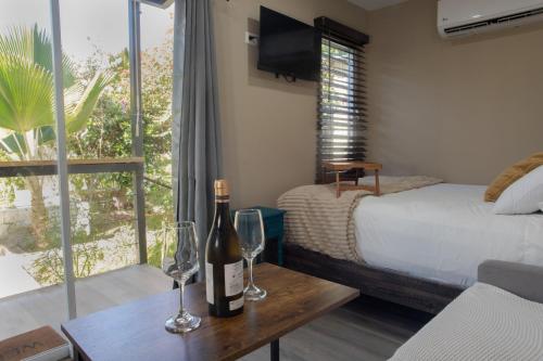 a bedroom with a bottle of wine and two glasses on a table at Garden to Table Experience - Unit 101 in Rincon