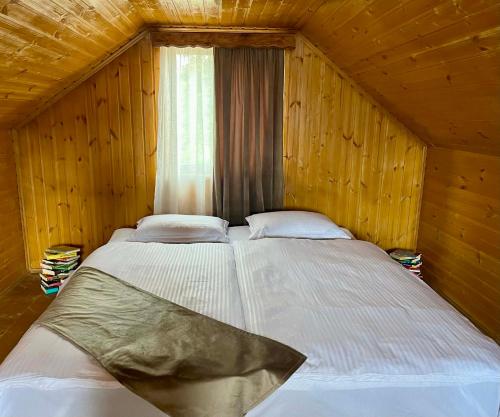 a large bed in a wooden room with a window at Orbis Bude in Samshvilde