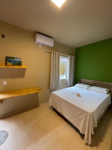a bedroom with a bed with a green wall at Casa Dona Vilma in Barreirinhas