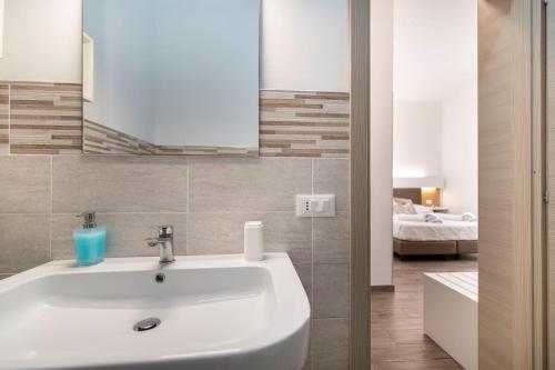 a bathroom with a white sink and a bedroom at La Dimora del Passante in San Vito lo Capo