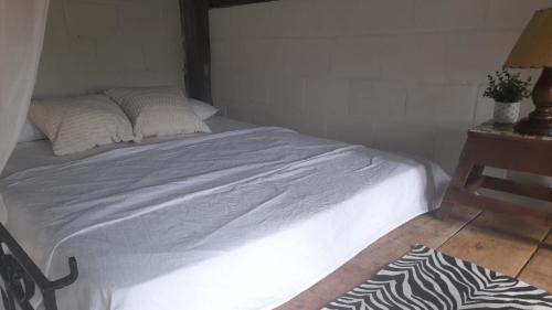 a bed with white sheets and pillows next to a table at Alojamiento campestre in Cali