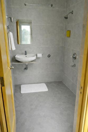 a bathroom with a sink and a shower with a mirror at Forest Grandeur Resort in Anantnāg