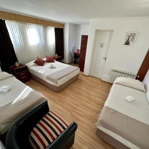 a hotel room with two beds and a chair at KELMAN Hotel in Perito Moreno