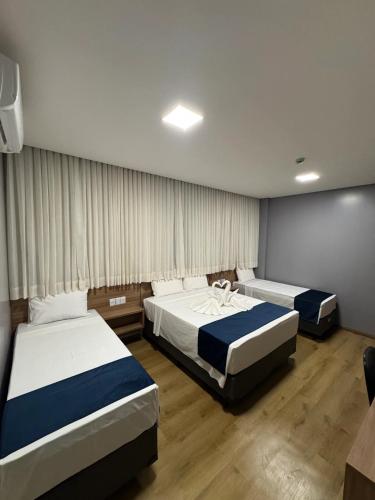 a hotel room with two beds and curtains at Hotel Bonfim in Silvânia